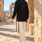 True Balance של 613, חולצת ציצית שחורה עם שרוול ארוך, צילום חוץ לצד מבני אבן